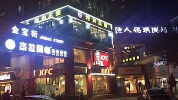 A KFC restaurant with a prominent sign, located on a busy street with other commercial buildings.