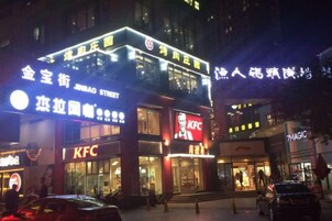 Un restaurante KFC con un letrero llamativo, ubicado en una calle concurrida junto a otros edificios comerciales.