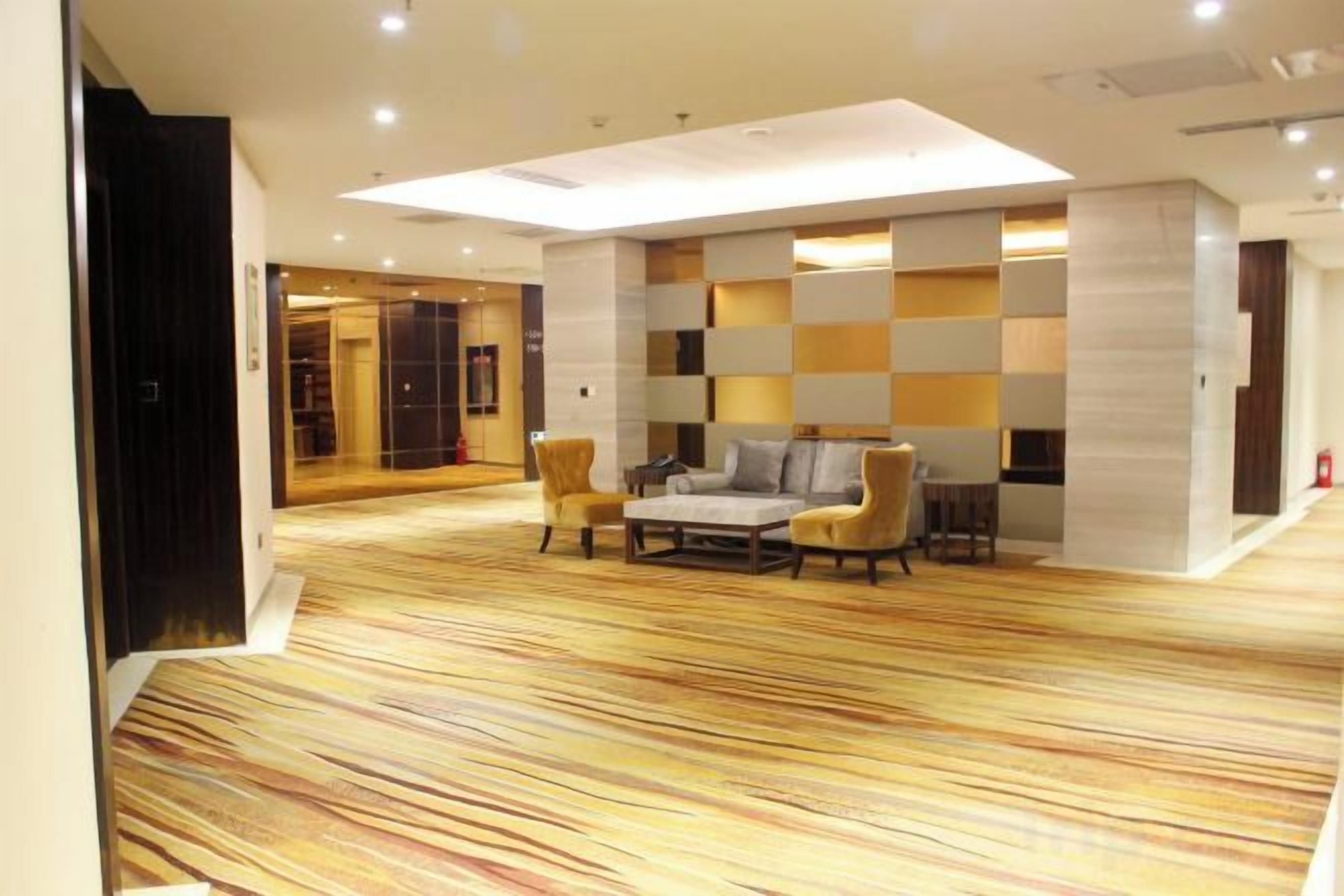 A modern lobby with a patterned carpet, a sofa set, and a wall with a geometric design.