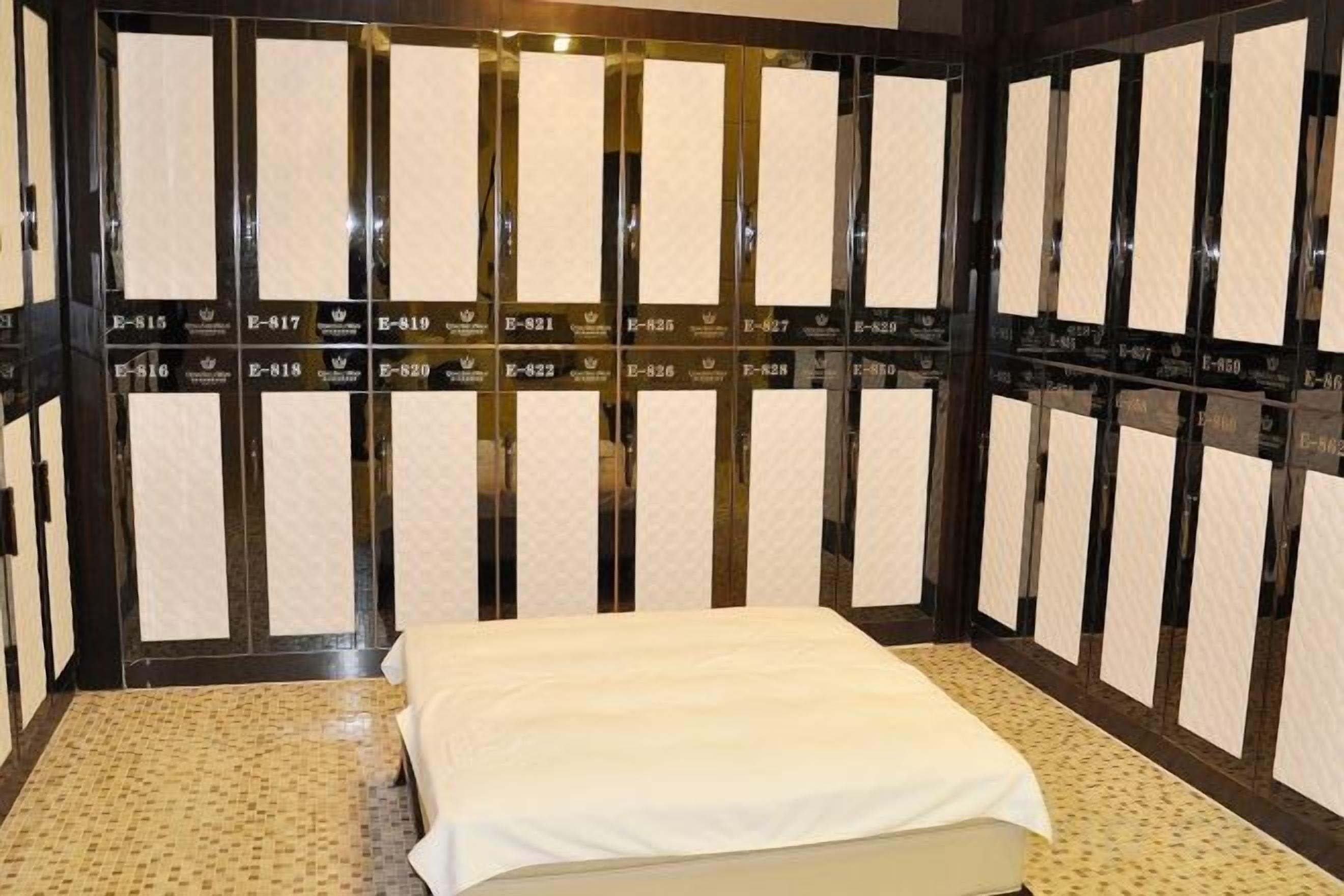 A room with a bed, a patterned floor, and a wall with vertical panels.