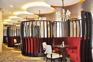 Un restaurante con mesas redondas y cabinas, una alfombra estampada y una lámpara moderna.