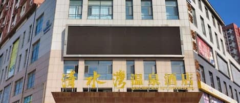 Un hotel de varios pisos con una señalización llamativa en un idioma extranjero.