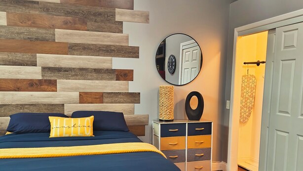 Een slaapkamer met een bed, een spiegel aan de muur, een dressoir en een deur.