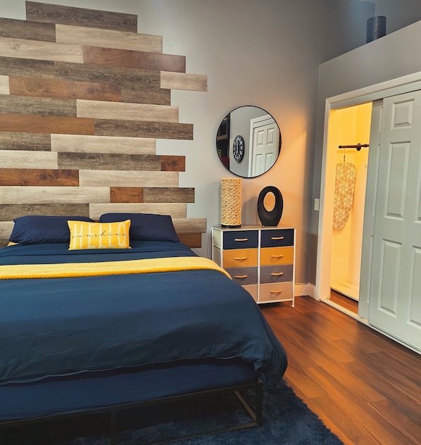 Een slaapkamer met een bed, een spiegel aan de muur, een dressoir en een deur.