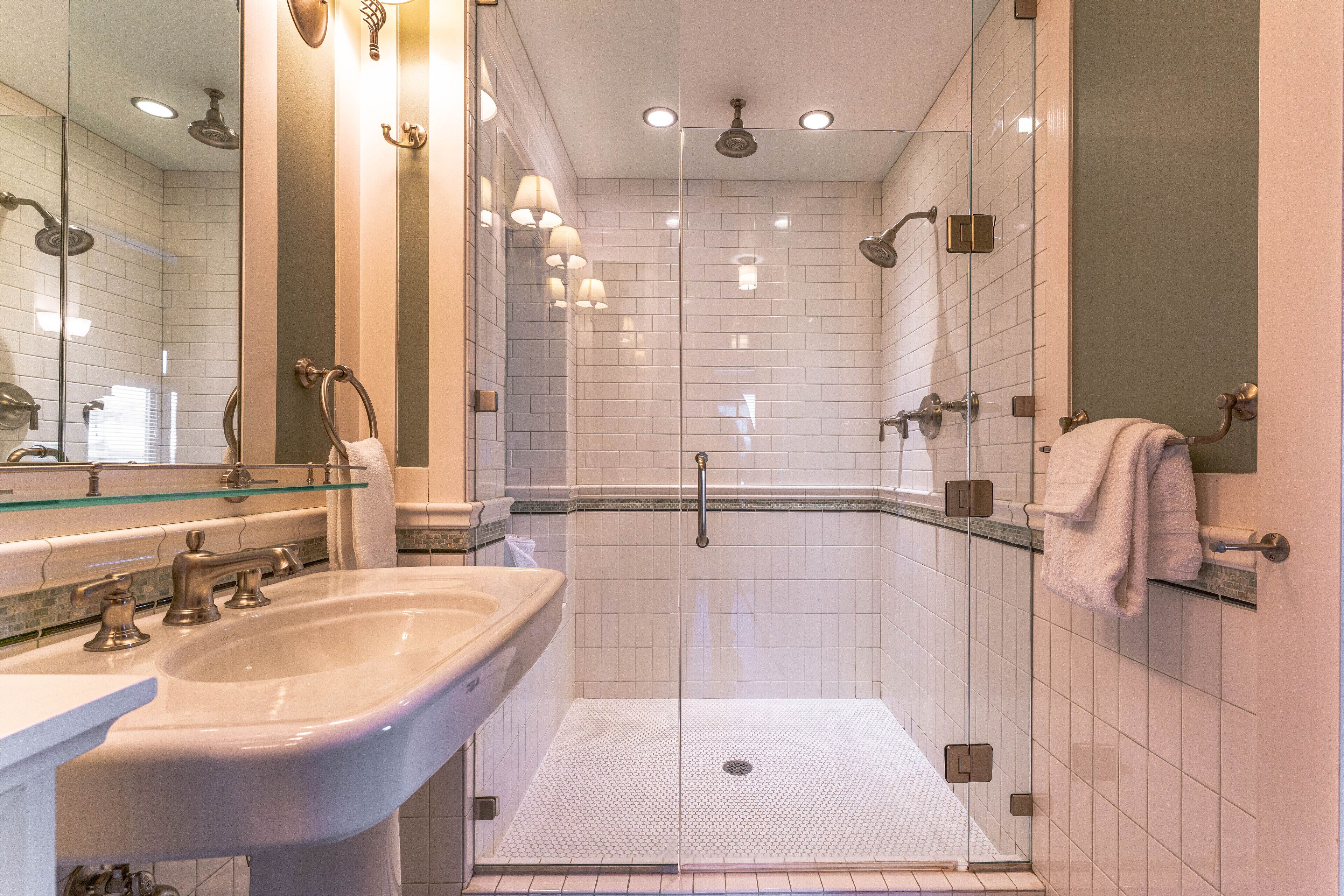 Une salle de bain moderne avec une douche à parois de verre, un lavabo et un miroir.