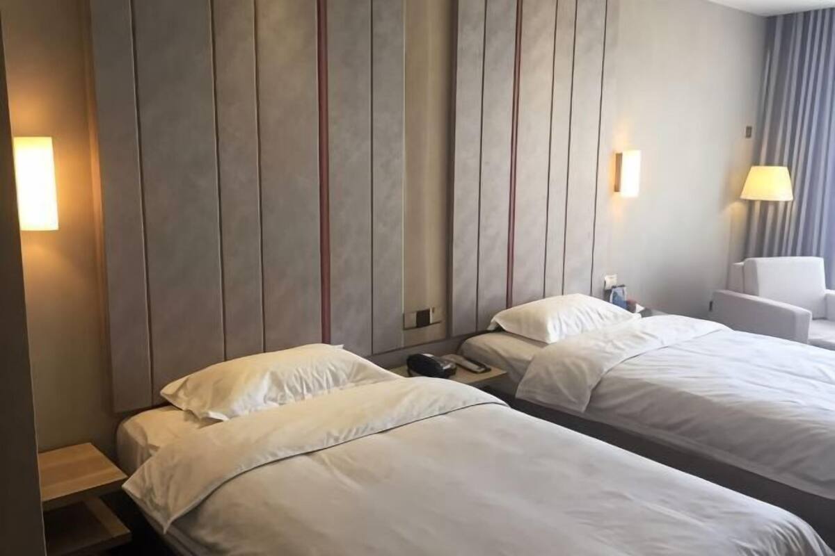 Une chambre d’hôtel avec deux lits, une table de chevet, une lampe et une chaise.
