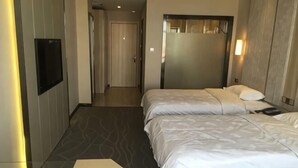 A hotel room with a bed, a TV, and a door leading to another room.