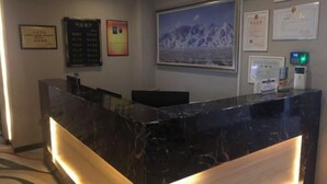 A reception desk with a marble finish, a framed picture of mountains on the wall, and several certificates and plaques.
