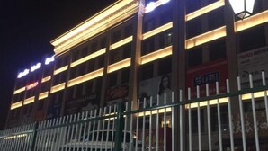 A multi-story building with illuminated signage and a white fence in front.