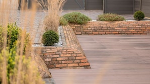 A residential area with a paved driveway, brick pathways, and a gated entrance.