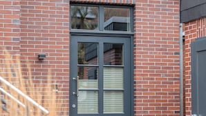 A brick building with a dark grey door and a small set of steps leading up to it.