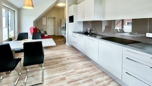 A modern kitchen with white cabinets, a black countertop, and a dining area with a table and chairs.