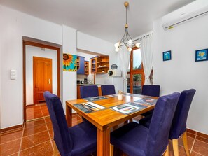 Un comedor con una mesa de madera, sillas azules y una lámpara en el techo.