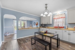 Une cuisine moderne avec une table et un banc en bois, des murs bleu clair et des armoires blanches.