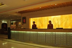 A reception desk with two staff members, a wooden panel design, and a modern reception area. - Zizhou International Hotel (Santai)