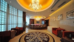 A hotel lobby with a central chandelier, a round dining table, and red seating areas. - Zizhou International Hotel (Santai)