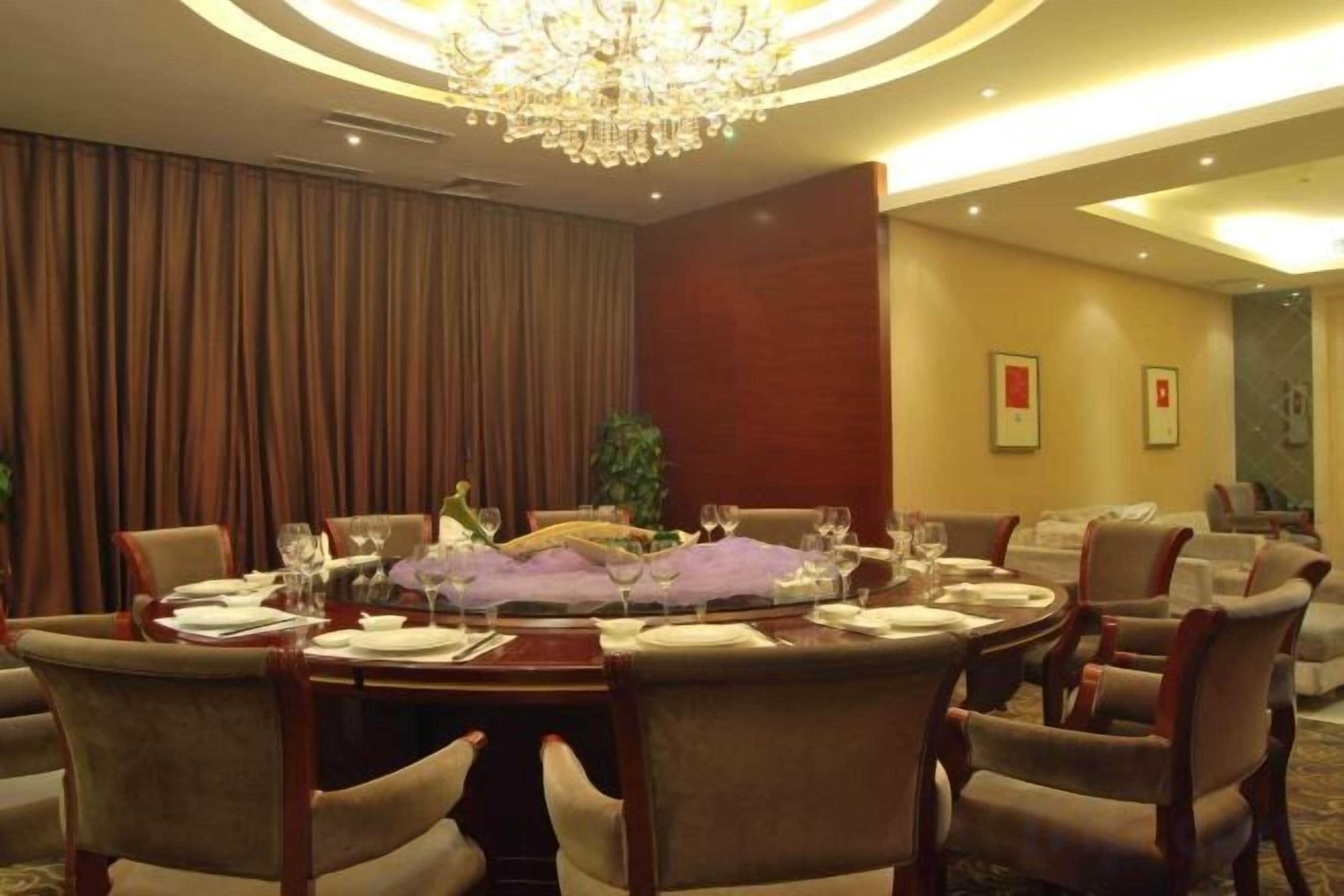 A conference room with a round table, chairs, and a chandelier.