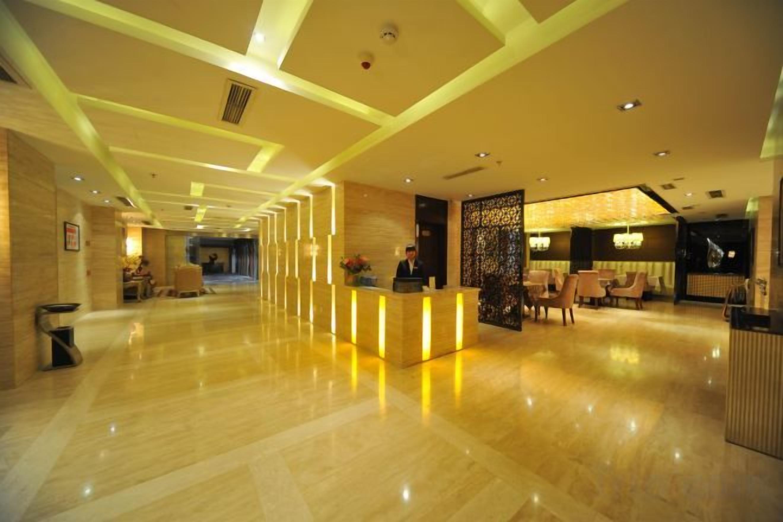 A hotel lobby with a reception desk, seating area, and a decorative partition.