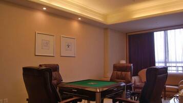Una habitación con mesa de billar, sillones de cuero y cuadros en la pared.