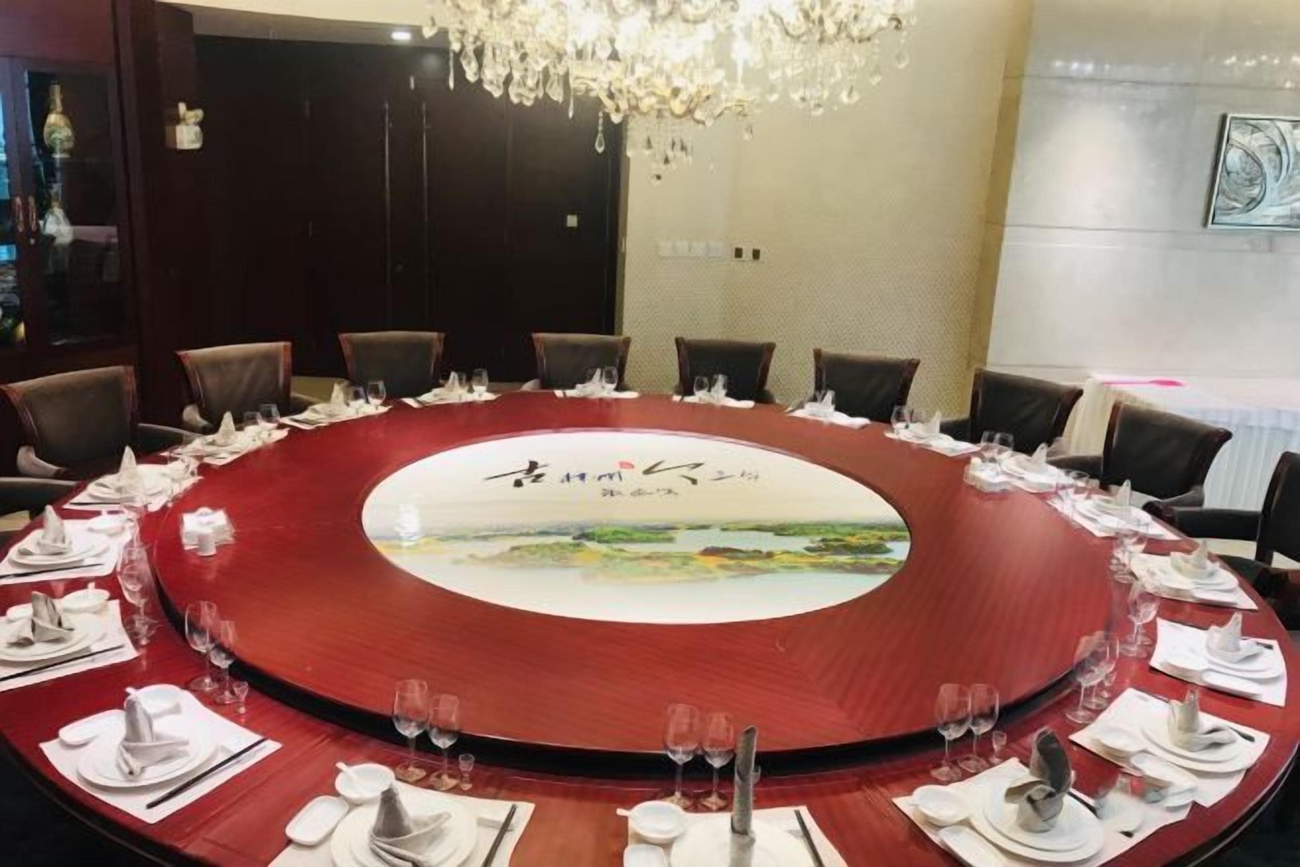 Una mesa redonda con mantel rojo, rodeada de sillas, dispuesta para una reunión.