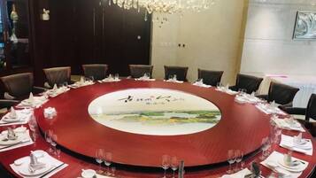 Una mesa redonda con mantel rojo, rodeada de sillas, dispuesta para una reunión.