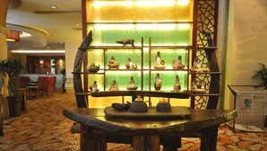 A lobby with a traditional wooden table, a green-lit display of pottery, and patterned carpet flooring. - Zizhou International Hotel (Santai)