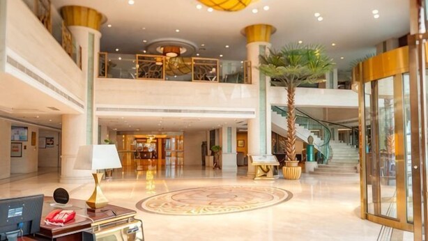 A spacious lobby with a central circular floor design, a staircase, and a reception desk. - Zizhou International Hotel (Santai)