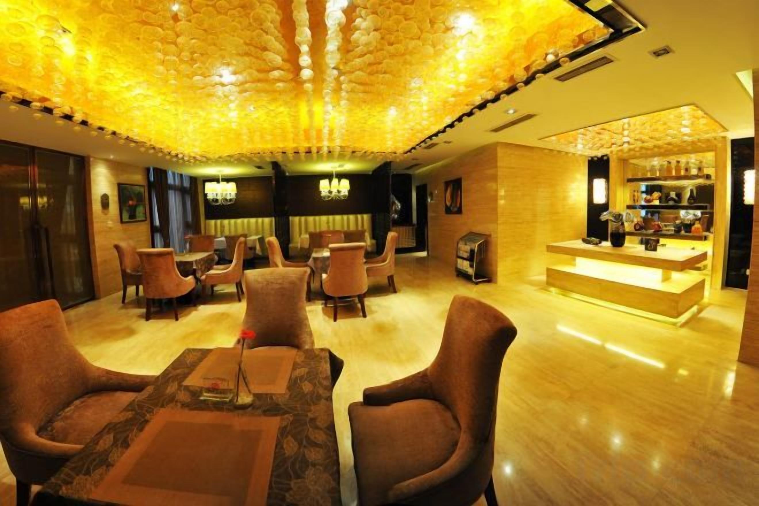 Un hall de hotel con un área de estar central, un bar y una recepción.