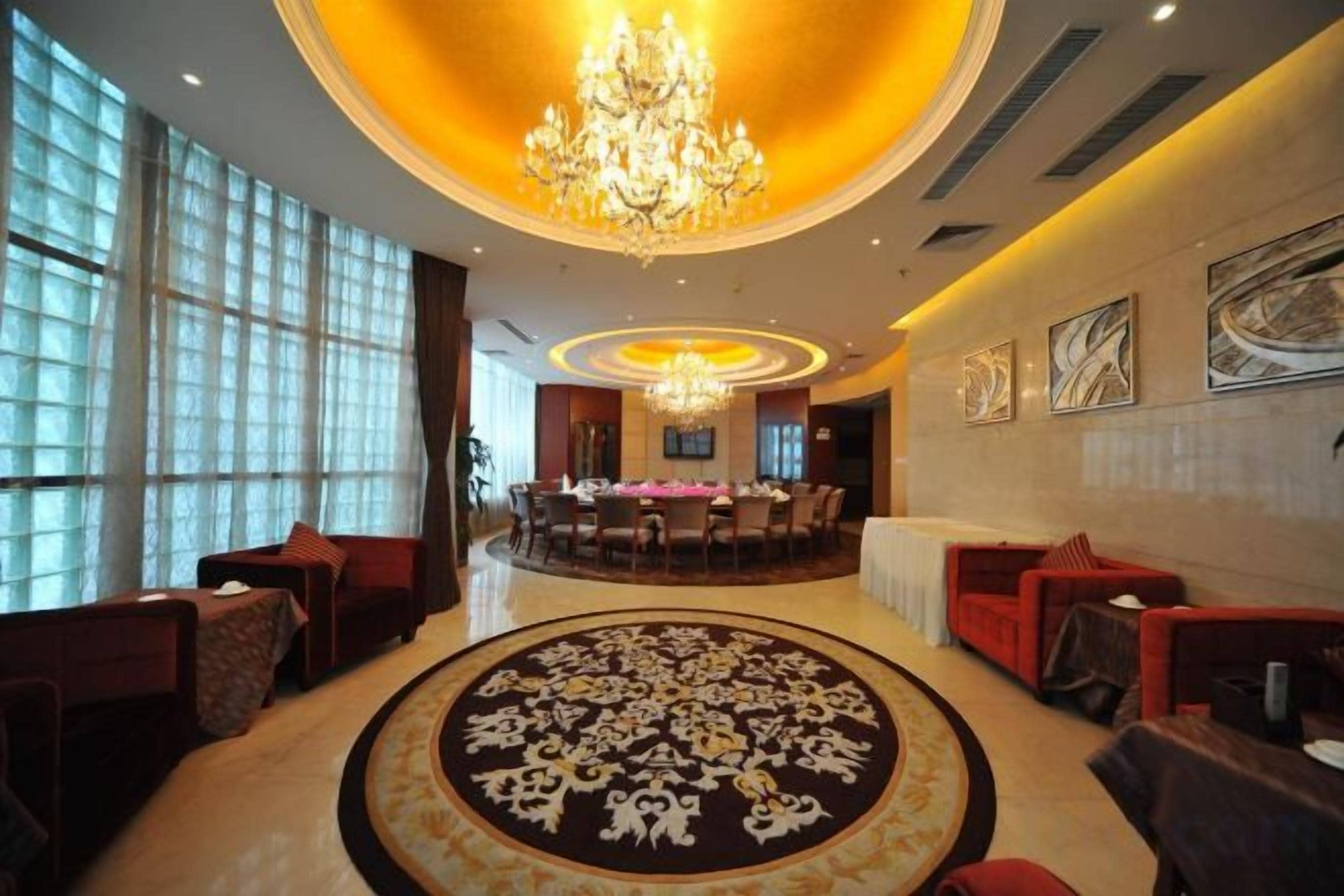 A hotel lobby with a chandelier, round tables, and seating areas.