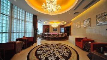 A hotel lobby with a chandelier, round tables, and seating areas.