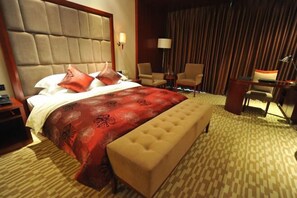 A hotel room with a large bed, a bench, two chairs, a desk, and a lamp. - Zizhou International Hotel (Santai)