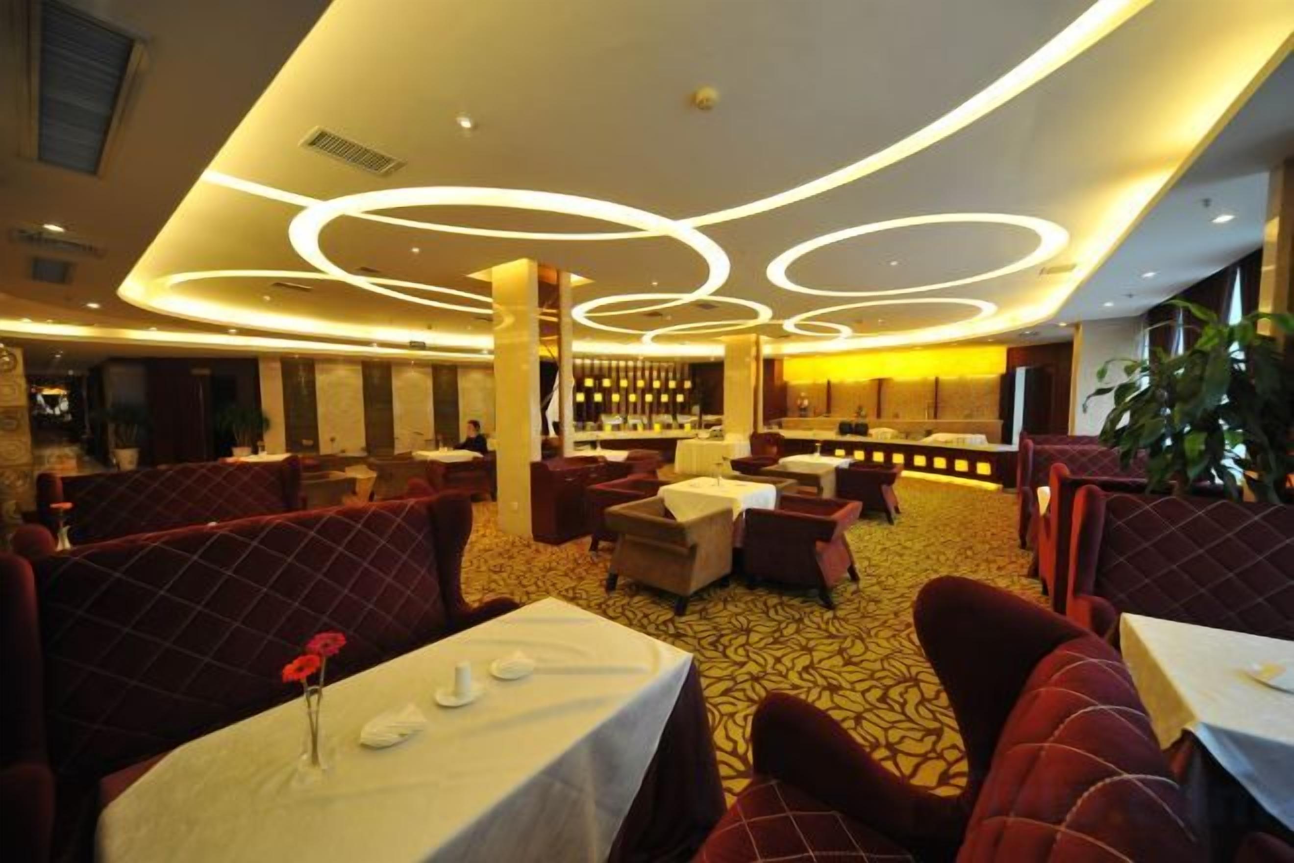 A restaurant with round tables, red upholstered booths, and a bar area.