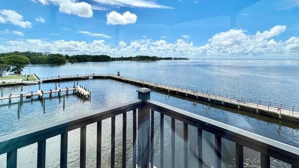 Une vue sur le bord de l’eau depuis un balcon, avec un ciel dégagé et une eau calme.