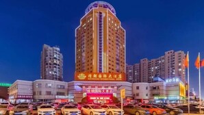 Un hôtel avec une enseigne bien visible, plusieurs étages et un parking rempli de voitures.