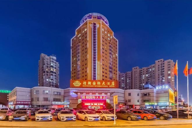 A multi-story hotel with a prominent sign, surrounded by other buildings and a parking lot.