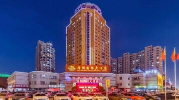 A multi-story hotel with a prominent sign, surrounded by other buildings and a parking lot.