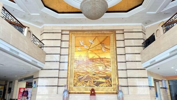 Un hall d’entrée spacieux, orné d’une grande fresque murale, doté d’un sol poli et d’un design de plafond moderne.