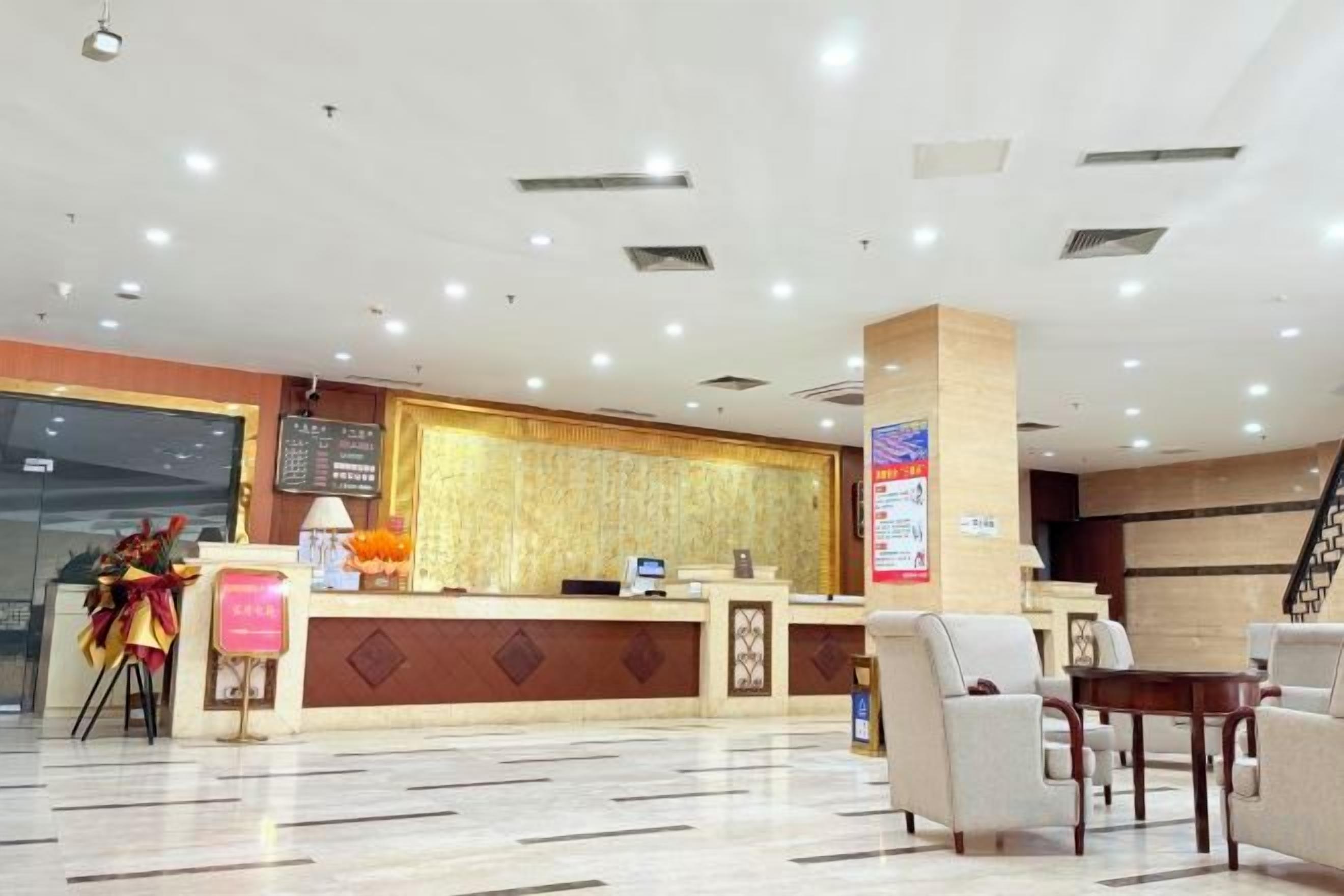 A hotel reception area with a reception desk, seating area, and a staircase.