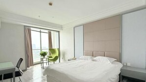 Une chambre d’hôtel moderne, dotée d’un grand lit, d’un bureau, d’une chaise et offrant une vue sur la ville.