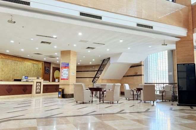 A hotel lobby with a reception desk, seating area, and a staircase.