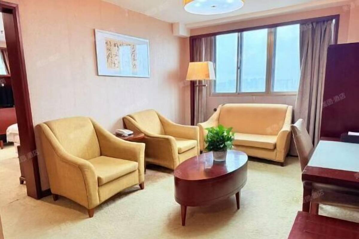 Hotellihuone, jossa on kaksi sohvaa, sohvapöytä, lamppu ja ikkuna, jossa on verhot.