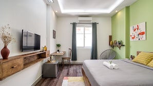 Quarto moderno com cama, escrivaninha, cadeira e televisão.
