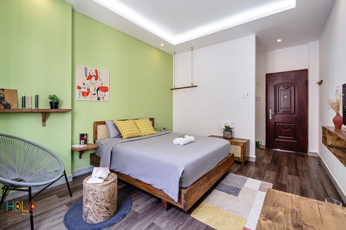 Une chambre moderne avec un lit en bois, des murs verts et un plancher en bois.