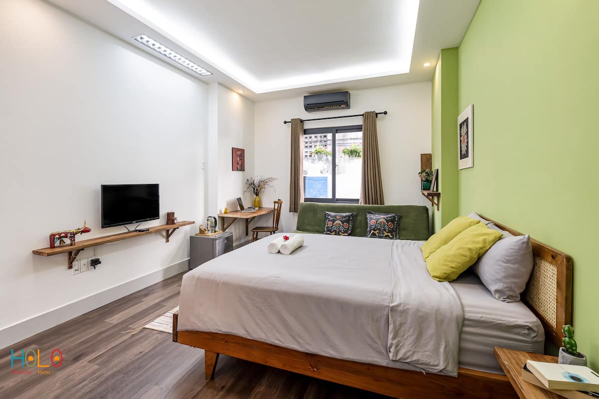 Une chambre d’hôtel moderne avec un lit en bois, un téléviseur à écran plat, un bureau et une fenêtre avec des rideaux.