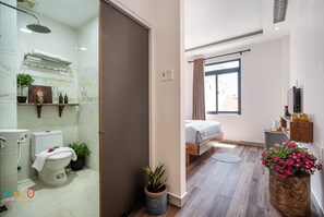 Experience a bright and airy space with a large window, a comfortable bed, and a modern bathroom.