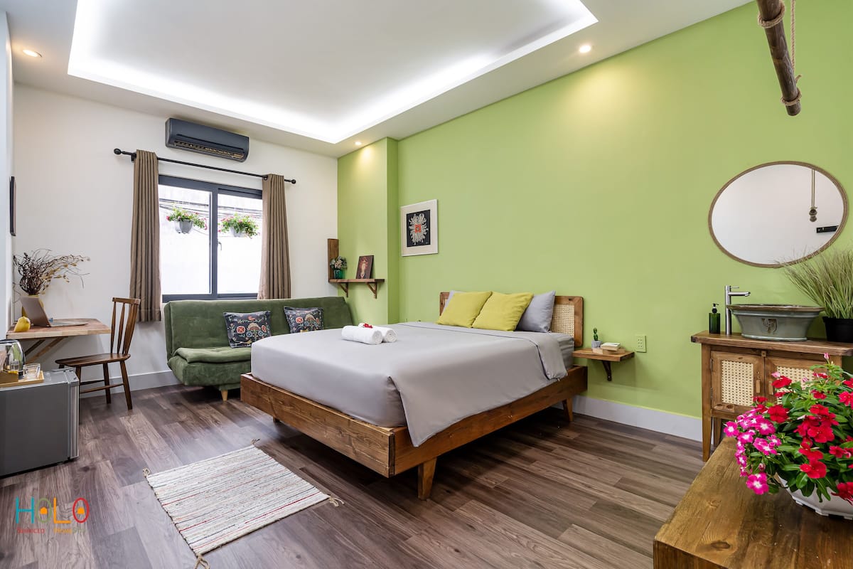 Une chambre à coucher avec un lit en bois, des murs verts et un bureau avec une chaise.