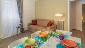Ein Essbereich mit Tisch für vier Personen, einer Couch, einer Lampe und einer Heizung.