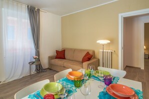 A dining area with a table set for four, a sofa, a lamp, and a radiator.