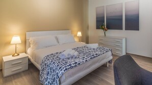 Ein Schlafzimmer mit einem Bett, Nachttischen, einem Sessel und Kunstwerken an der Wand.
