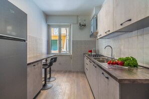 A compact kitchen with a refrigerator, a sink, and a window.